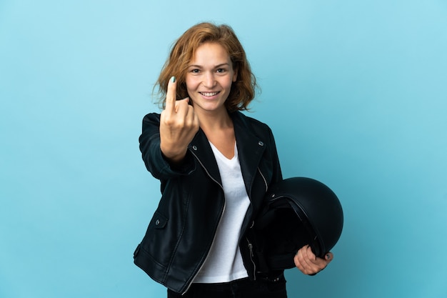 Georgian girl holding a motorcycle helmet isolated on blue wall doing coming gesture