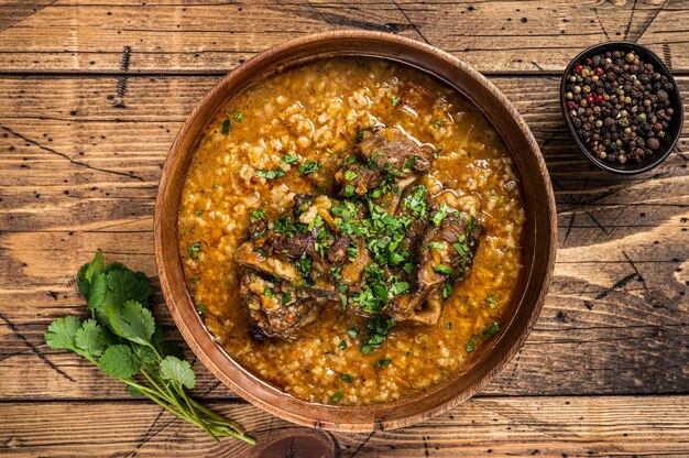 Georgian Kharcho lamb meat soup with rice, tomatoes and spices in a wooden bowl