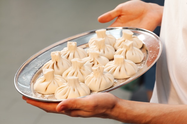 Georgian khinkali tray in hands close up