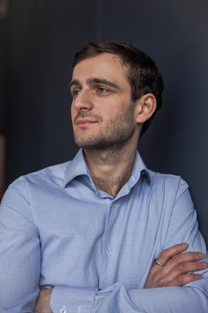 A Georgian man in a shirt stands against a blue wall