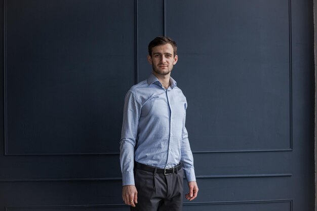 A Georgian man in a shirt stands against a blue wall