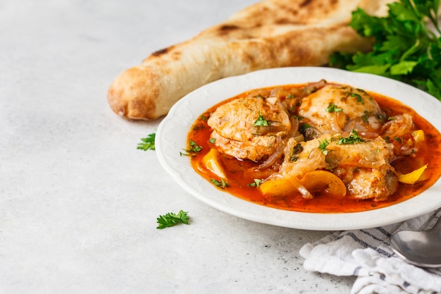 Georgian traditional chicken chakhokhbili in a white plate.