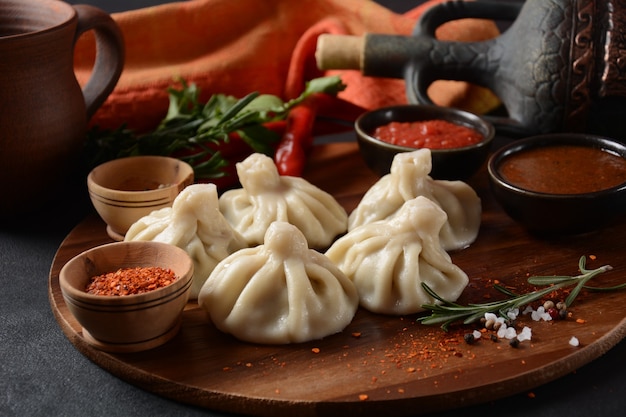 Georgische dumplings Khinkali met vlees en rode peper, traditionele nationale Georgische keuken. Khinkali met lokale sauzen - tkemali, satsebeli, adzhika.