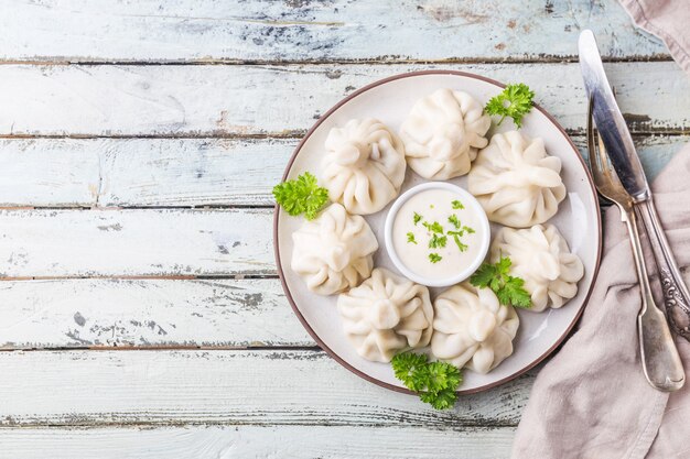 Georgische dumplings Khinkali met vlees, greens en saus op witte plaat