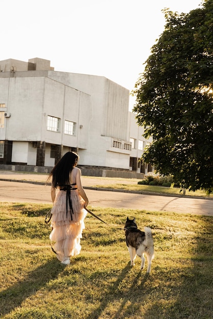 Georgische vrouw die met siberische husky loopt bij zonsondergang aantrekkelijk meisje met haar lieve hond die op straat speelt