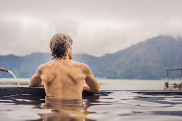 Geothermal spa Man relaxing in hot spring pool Young man enjoying bathing relaxed in a blue water lagoon tourist attraction