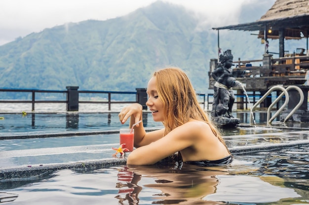 Geothermal spa woman relaxing in hot spring pool against the lake hot springs concept drinking guava