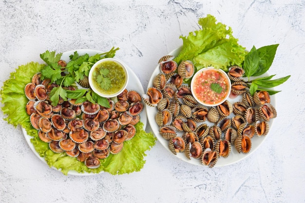 Gepelde kokkels met zeevruchtensaus en groentesaladesla op plaatachtergrond, Verse ruwe schaaldierenbloedkokkel oceaan gastronomische zeevruchten in het restaurant, overzees shellsvoedsel