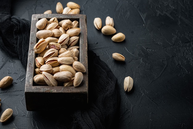 Gepelde, ongezouten pistachenoten, op zwarte gestructureerde achtergrond met ruimte voor tekst