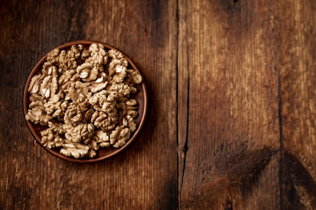 Gepelde walnoten op een bord Donkere houten achtergrond Vegetarische gezonde voeding Uitzicht van bovenaf Plaats voor uw tekst