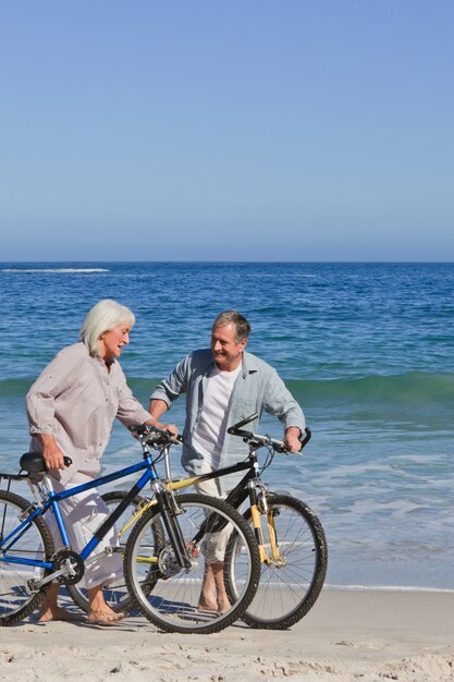 Gepensioneerd echtpaar met hun fietsen op het strand