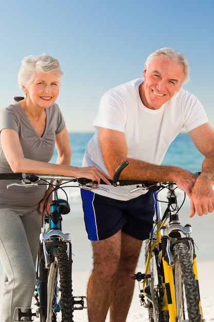 Gepensioneerd echtpaar met hun fietsen op het strand