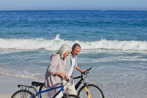 Gepensioneerd echtpaar met hun fietsen op het strand