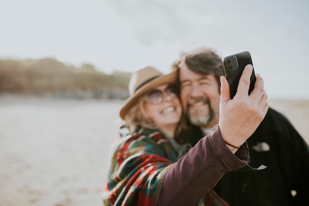 Gepensioneerd stel op reis maakt een selfie aan het strand