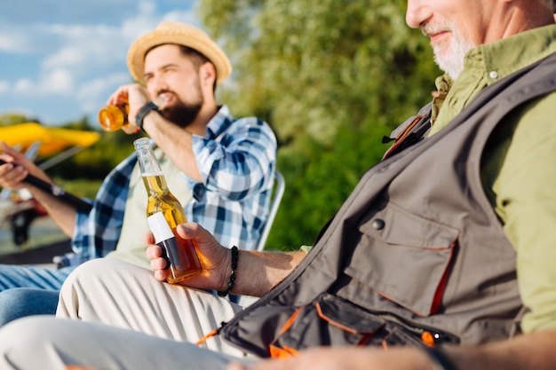 Gepensioneerde die tijd doorbrengt met een mannelijke vriend terwijl hij bier drinkt en vist