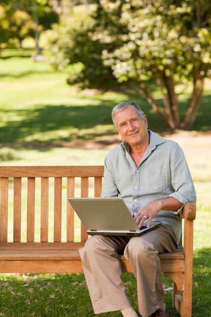 Gepensioneerde man aan het werk op zijn laptop in het park