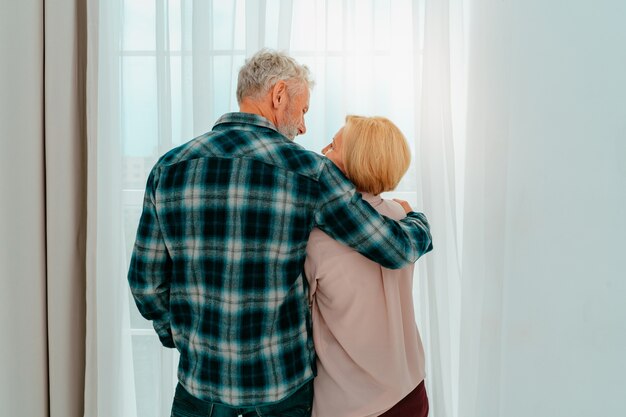 Foto gepensioneerde man en vrouw omhelzen elkaar thuis