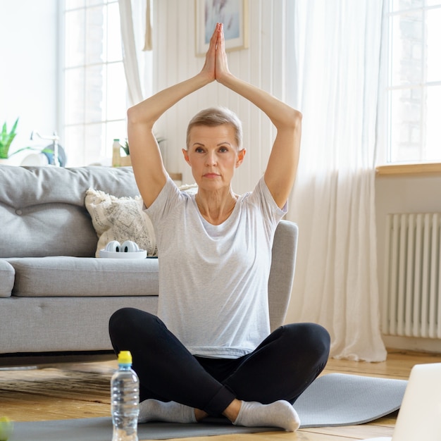 Gepensioneerde oudere vrouw geniet thuis van persoonlijke vervulling yoga wellness thuis