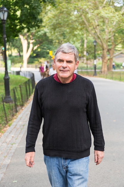 Foto gepensioneerde senior man in park, wandelen en ontspannen, lachende uitdrukking