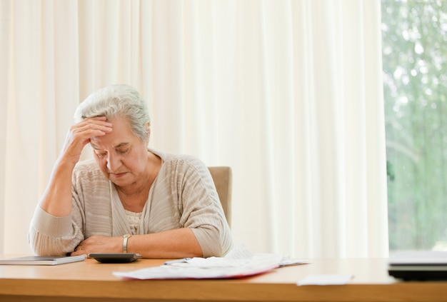 Gepensioneerde vrouw die haar binnenlandse rekeningen berekent