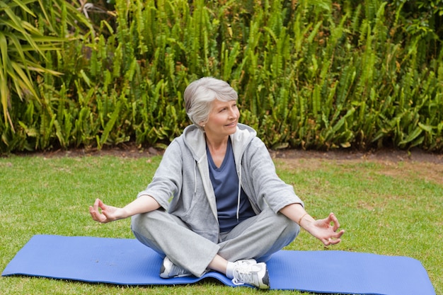 Gepensioneerde vrouw het beoefenen van yoga in de tuin