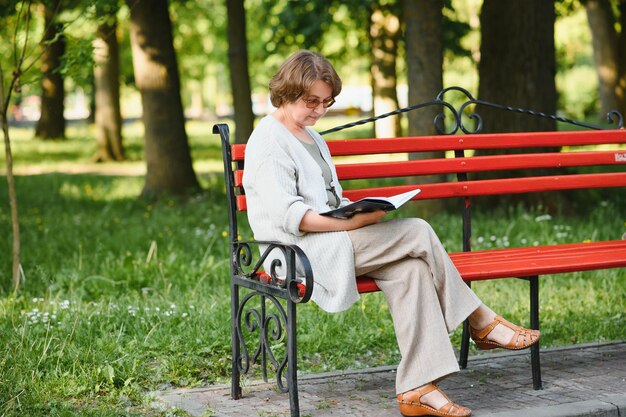 Gepensioneerde vrouw leest een boek op de bank