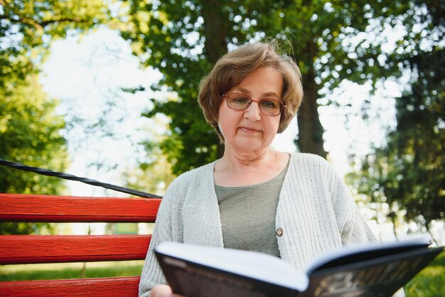 Gepensioneerde vrouw leest een boek op de bank