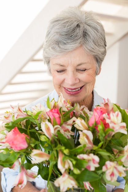 Gepensioneerde vrouw met boeket bloemen en glimlachen