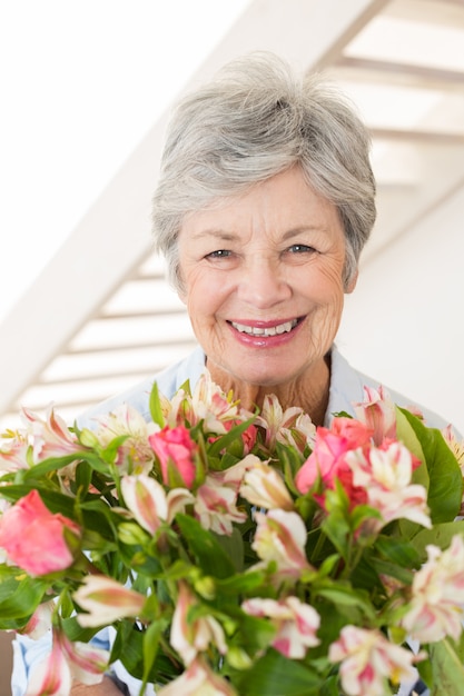 Gepensioneerde vrouw met boeket bloemen glimlachen op camera