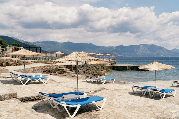 Geplaveid strand met ligstoelen en parasols vlakbij de zee