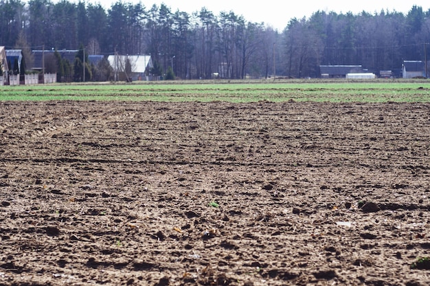 Geploegd veld in dorp in het voorjaar, met huizen