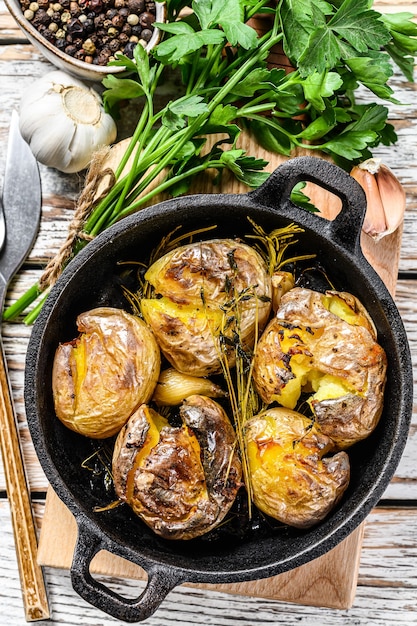 Gepofte aardappel met knoflook en rozemarijn in een pan. Witte achtergrond. Bovenaanzicht.