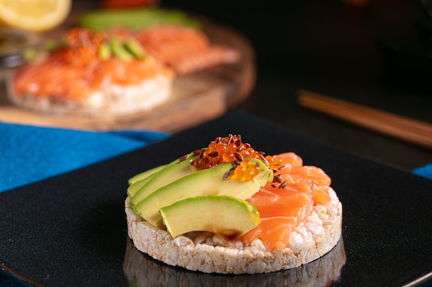 Gepofte rijstpasta met rauwe zalm en avocado op een donkere tafel