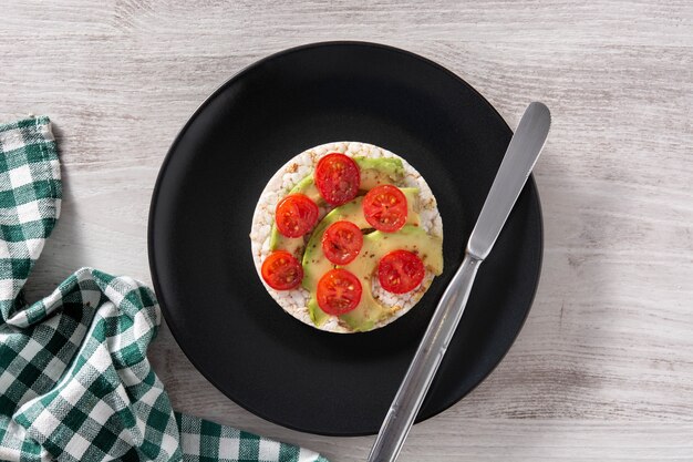 Gepofte rijstwafel met tomaat en avocado op houten tafel