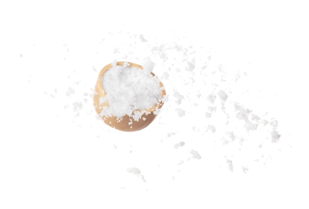 Geraffineerd zout valt naar beneden in een houten kom poeder witte zouten exploderen abstracte wolken vliegen kleine gemalen zout spatten in de lucht voedsel object element ontwerp witte achtergrond geïsoleerd hoge snelheid bevriezen