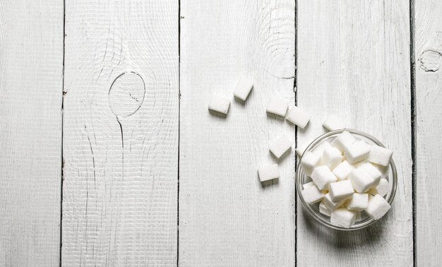 Geraffineerde suiker in de beker. Op een witte houten tafel.