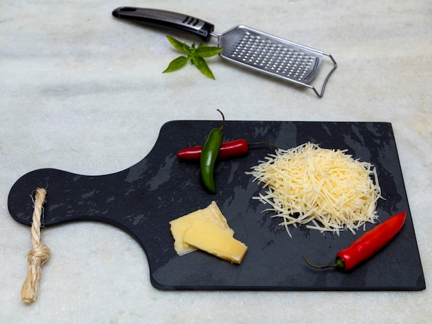 Geraspte parmezaanse kaas op zwarte steen met knoflook, ui, peper en andere kruiden