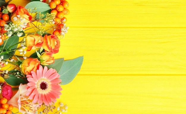 Foto gerbera en rozen op gele houten achtergrond