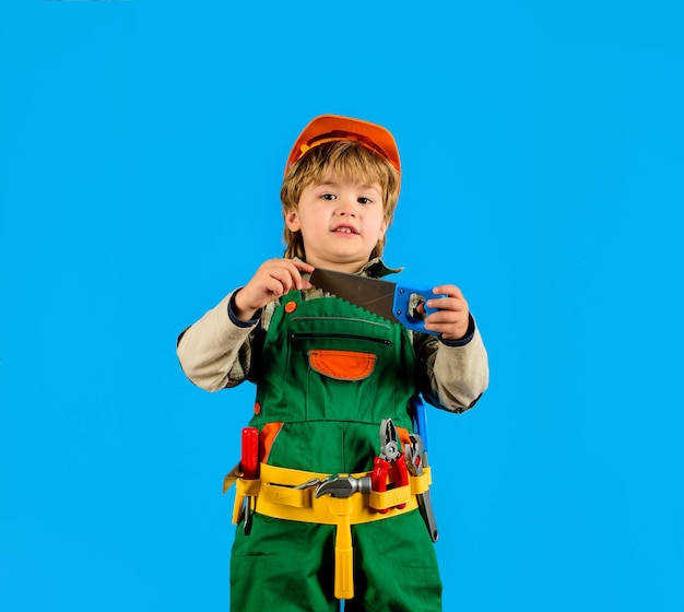 Gereedschap voor het bouwen van een kleine reparateur met een zaag kleine jongen in een uniforme gereedschapsriem voor de bouw
