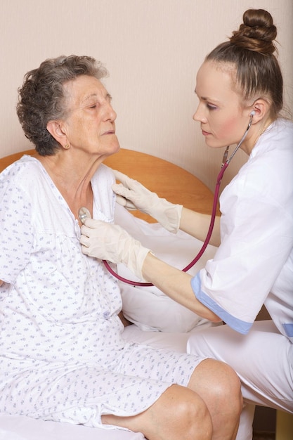 Geriatrician visits a senior woman between 70 and 80 years old in her ward