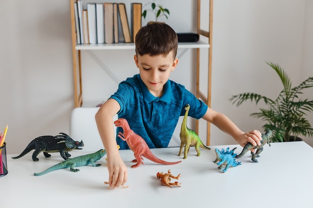 Gericht kind spelen met dinosaurussen thuis. Jongen die paleontologie leert door dino-speelgoed op zijn gemak. Concept van slim kind en vroeg onderwijs