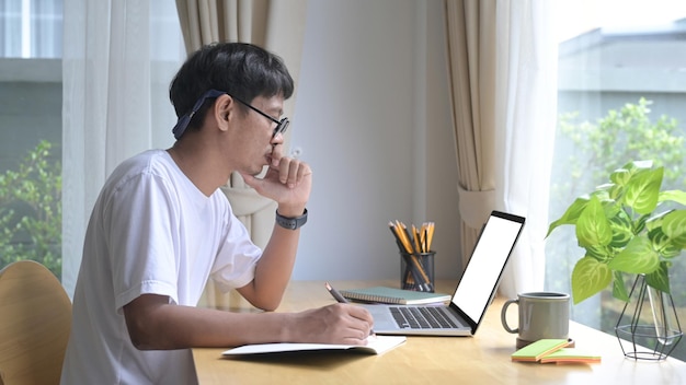 Gerichte aziatische man met laptop die e-mail leest die online werkt op kantoor aan huis