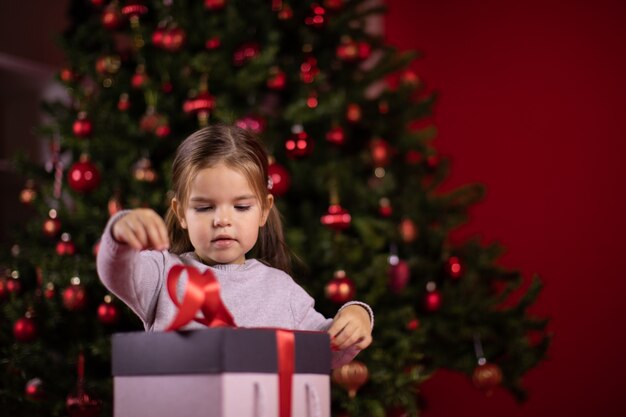 Gerichte babymeisje opening cadeau naast kerstboom