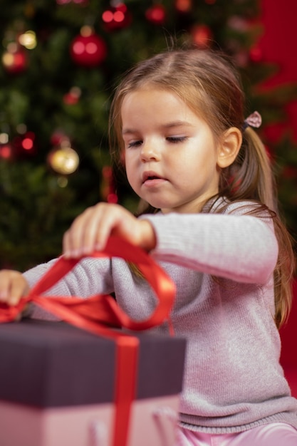 Gerichte babymeisje opening cadeau naast kerstboom