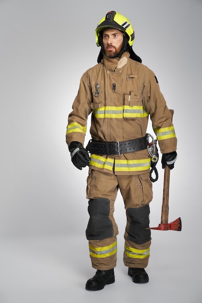 Foto gerichte brandweerman in volle gang met bijl die binnen loopt, vooraanzicht van een bebaarde brandweerman die draagt