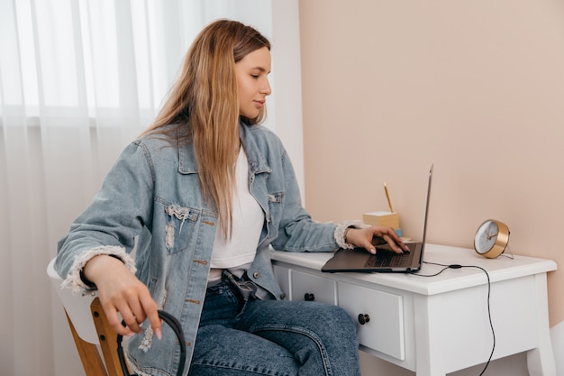 Gerichte jonge freelance vrouwenzitting op de lijst thuis met laptop en hoofdtelefoons