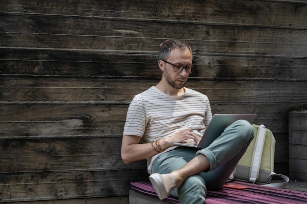 Gerichte jonge man met een bril die laptop gebruikt die typt op toetsenbord freelancer die online werkt