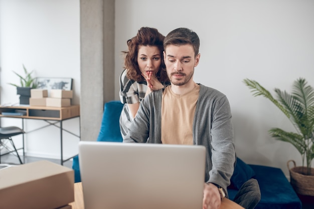 Gerichte schattige mannelijke kantoormedewerker en zijn verraste vrouwelijke collega die naar het laptopscherm staart