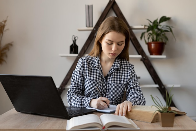 Gerichte tutor wiskundeleraar die les voorbereidt, maakt aantekeningen open studieboeken en zette laptop aan Gadgets en internet in studie en onderwijs Vrouw freelance student die op afstand werkt