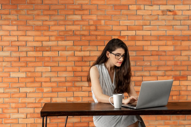 Gerichte zakenvrouw werken op laptop in café met bakstenen muur